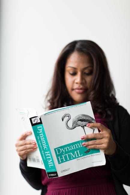 A professional gardener from gardenmaintenancenewham.co.uk is holding and reading a book titled 'Dynamic HTML' with a cover illustration of a flamingo bird. The garden maintenance scene is not directl